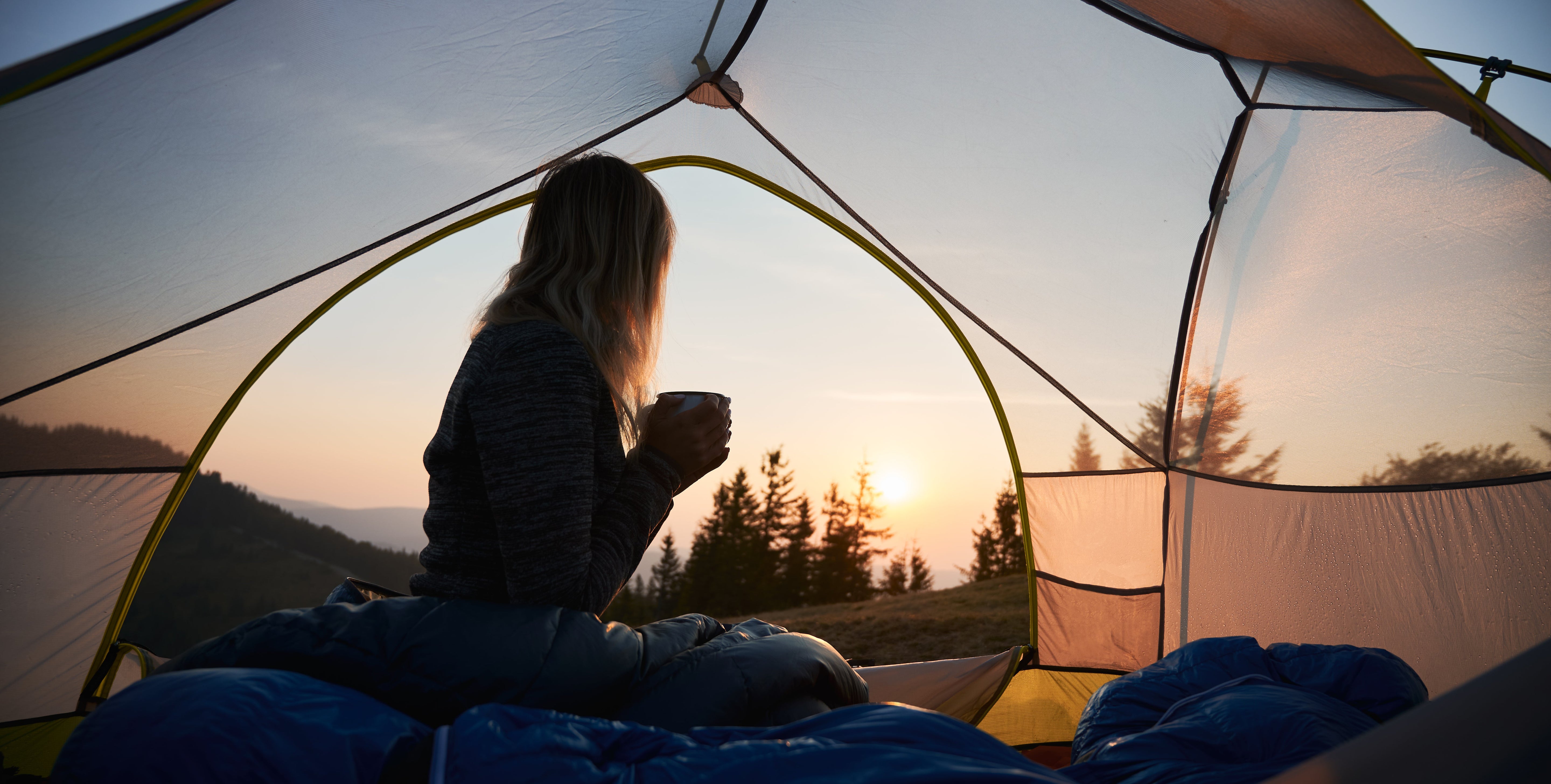 Mujer acampando en su periodo menstrual mientras que ve el atardecer
