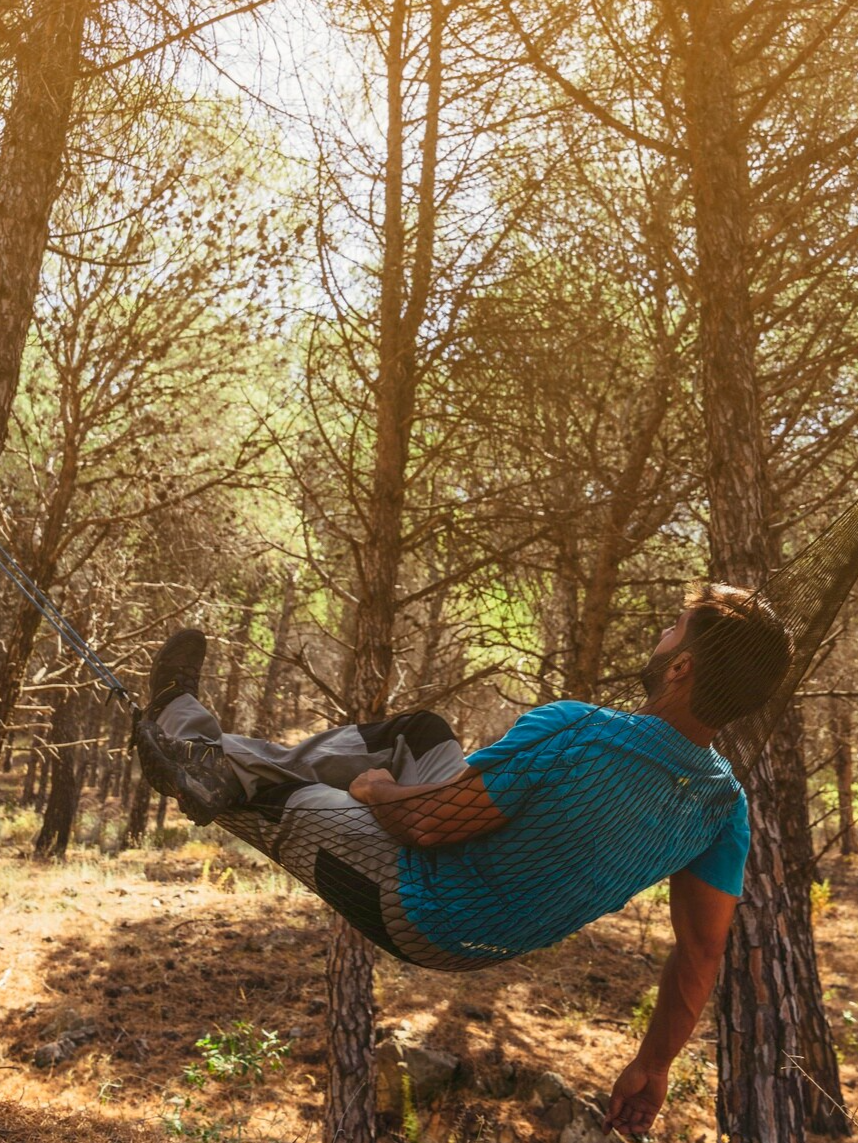 Hombre acostado en hamaca disfrutando de la naturaleza y mejorando su salud mental